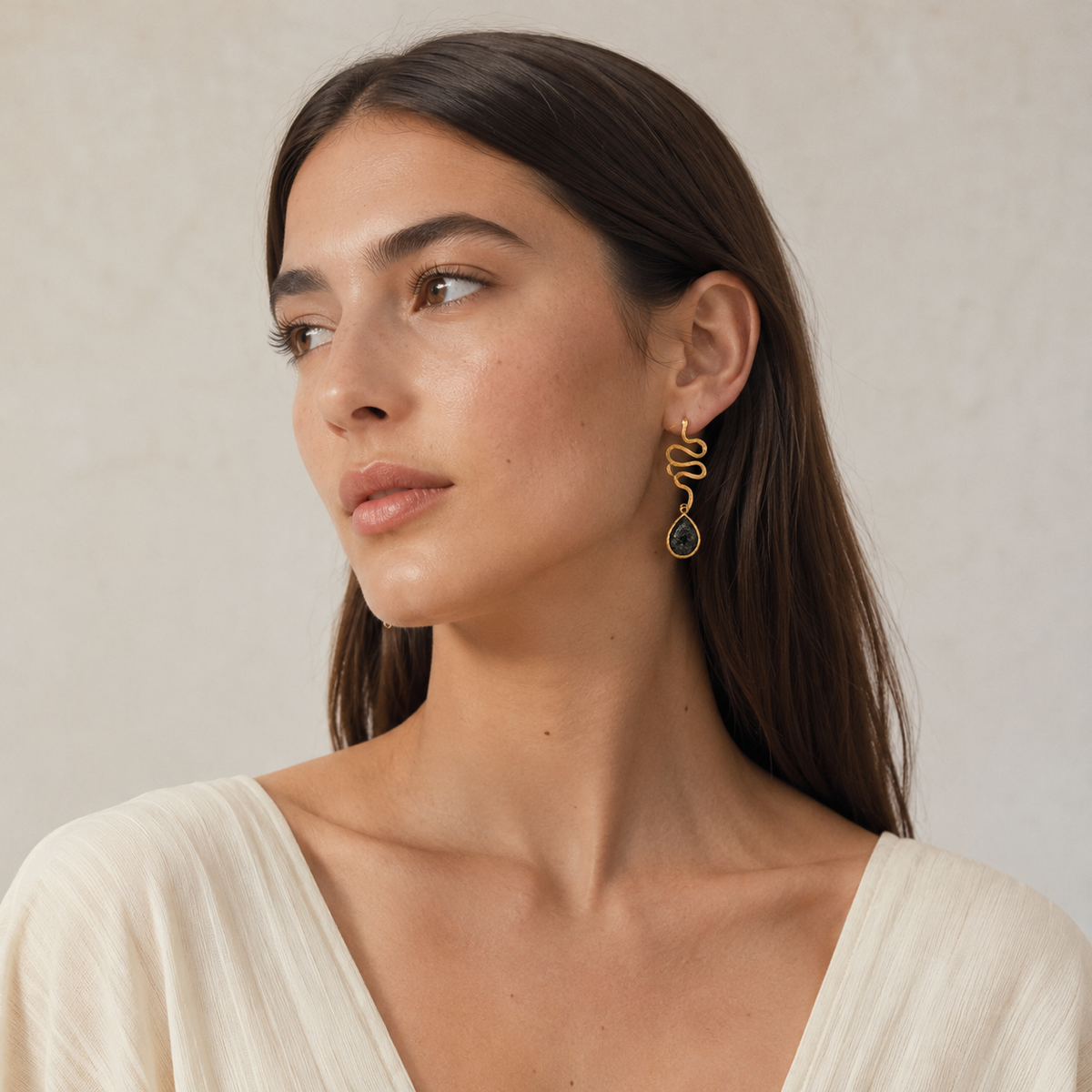 Pair of gold-plated snake shape earrings with dark teardrop drops.