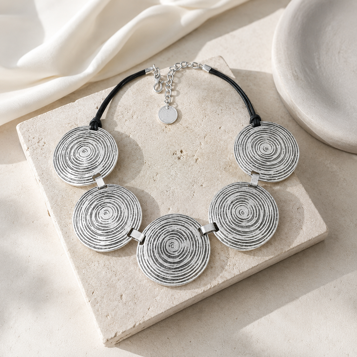 Silver spiral disc necklace styled as a bold statement piece.