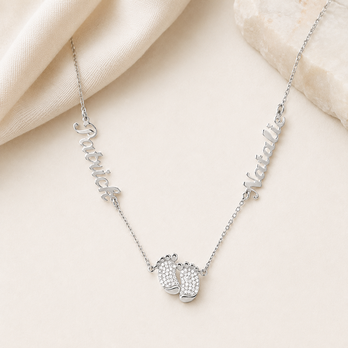 Personalized silver-tone necklace with a baby feet pendant on a clean background.