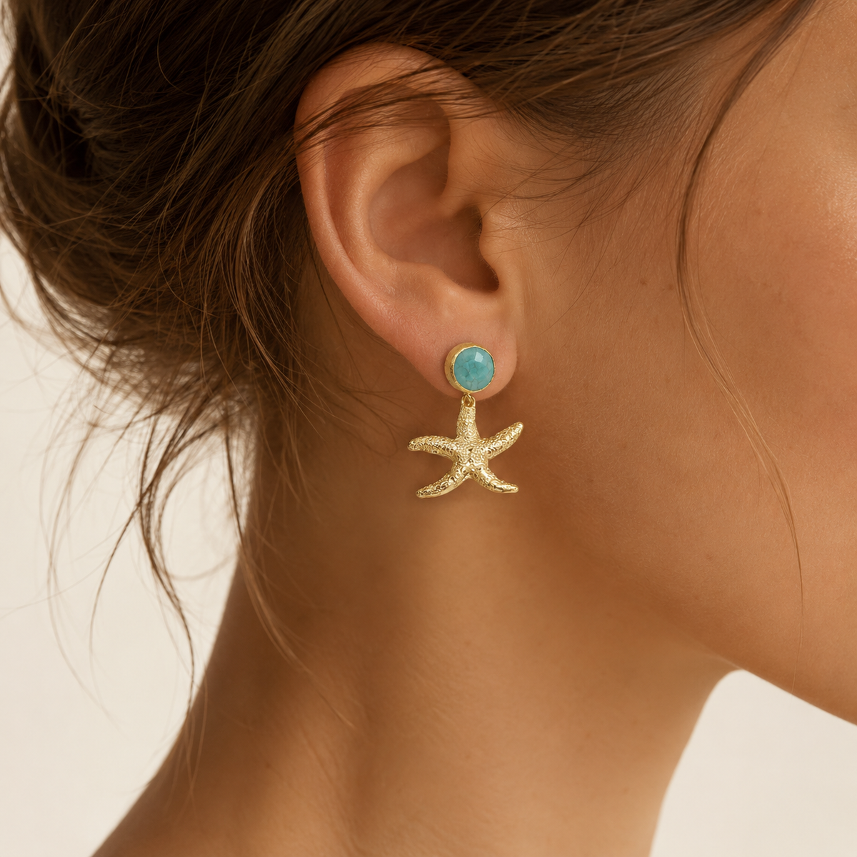 Pair of turquoise and gold starfish drop earrings shown front view.