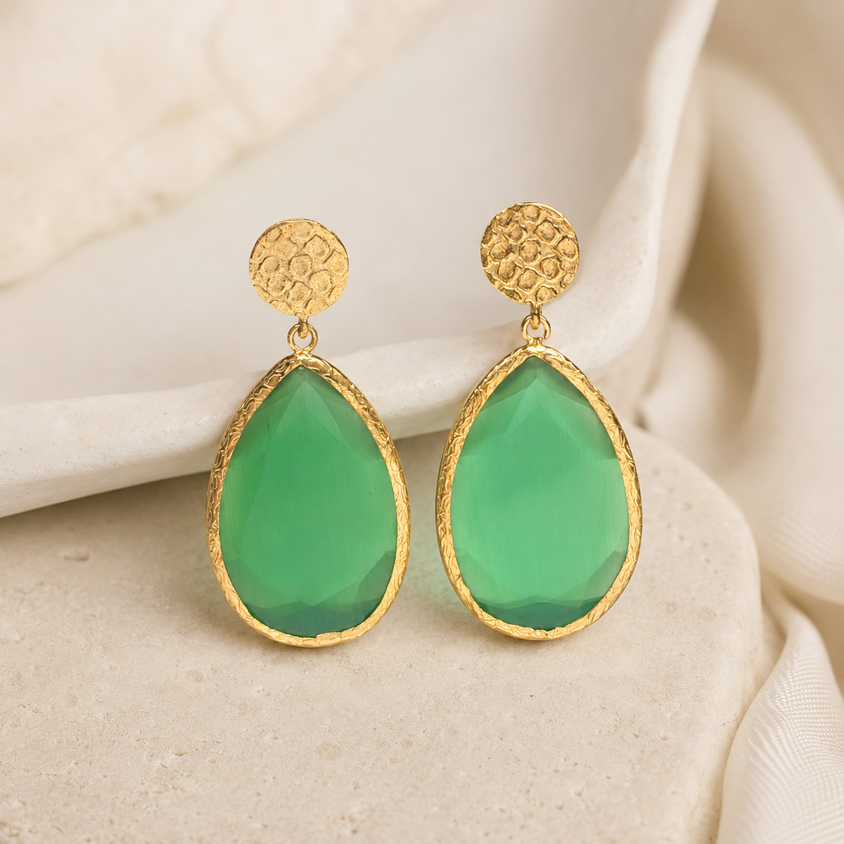 Gold-plated teardrop earrings with a faceted green smoky cat eye-style stone.
