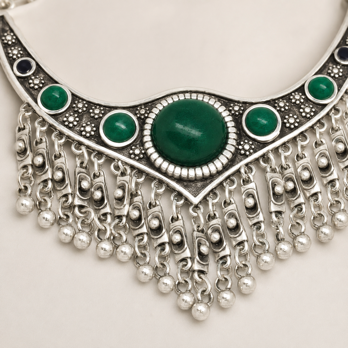 Close view of the green stones and textured silver-tone details.