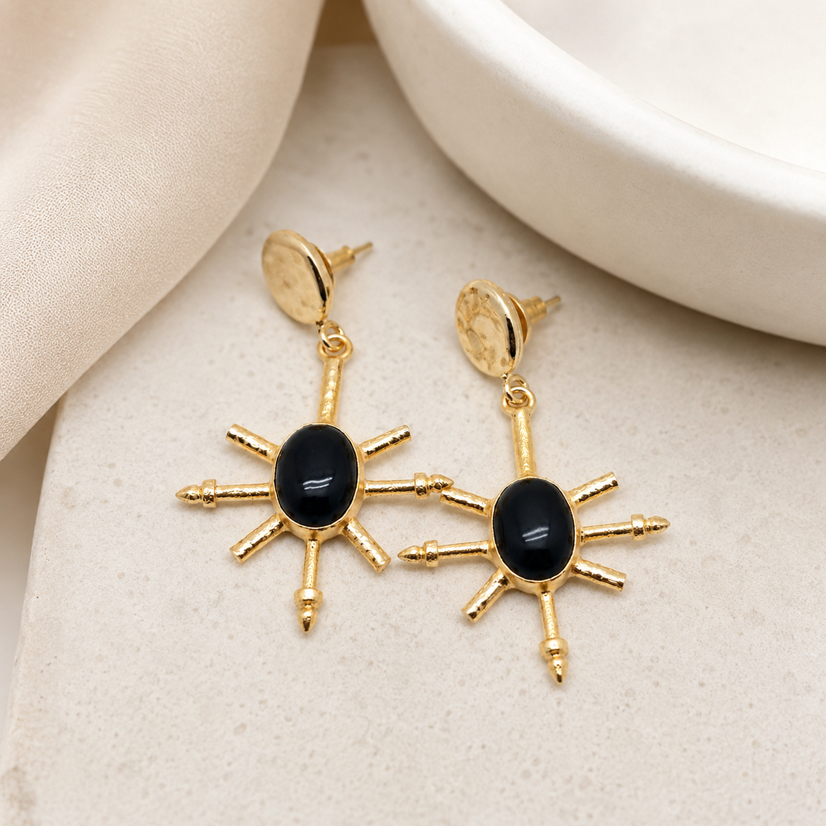 Gold-plated drop earrings with black onyx centers and a bold geometric shape.