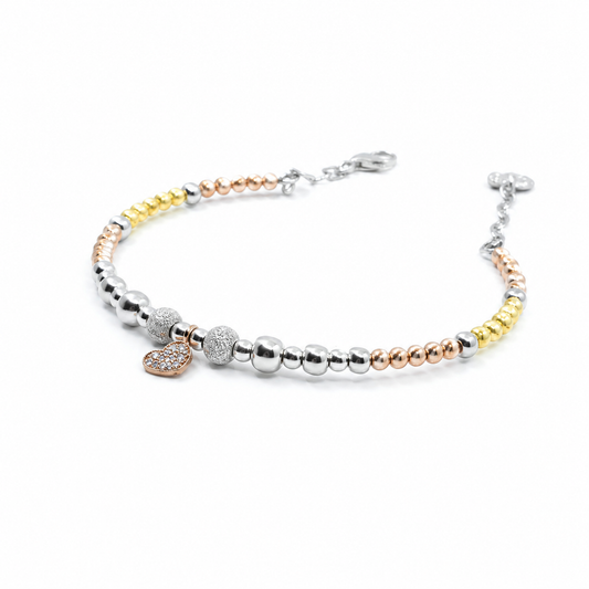 A bracelet with mixed metallic beads and a petite heart charm on a white background.