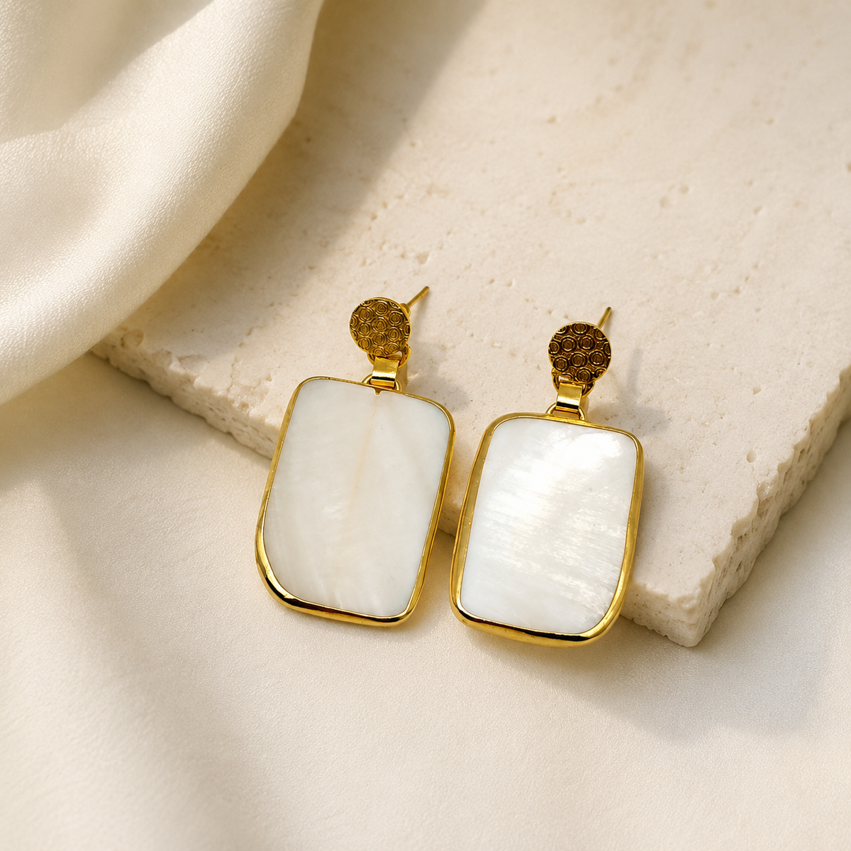 Gold plated rectangular earrings with clear quartz and a polished frame.