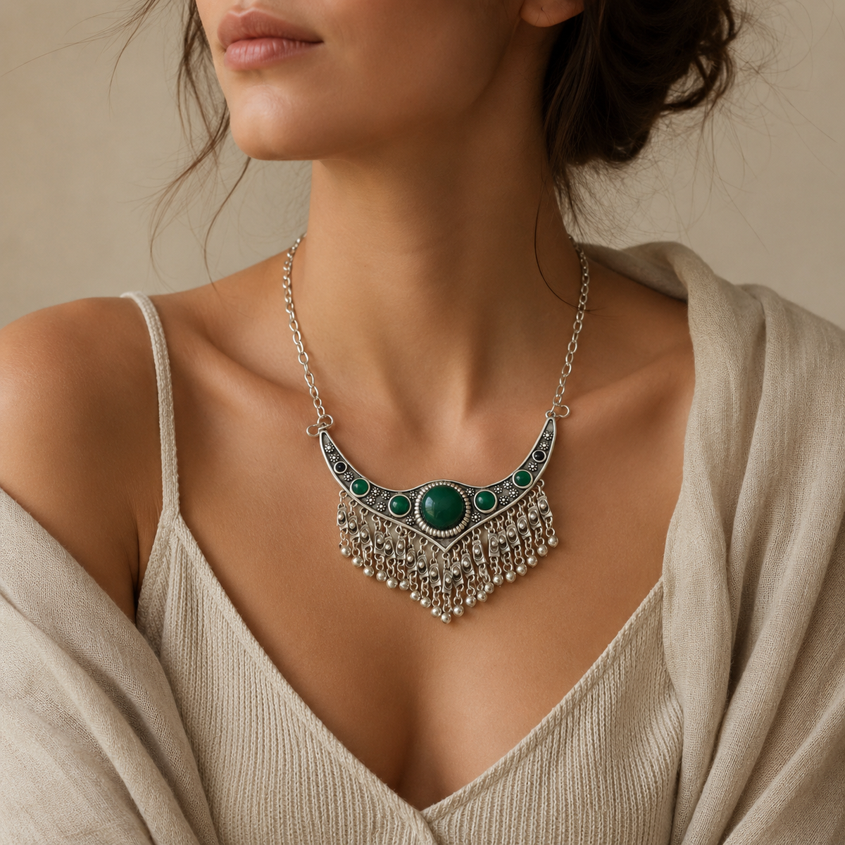 Statement necklace with a curved silver-tone shape and green stones.