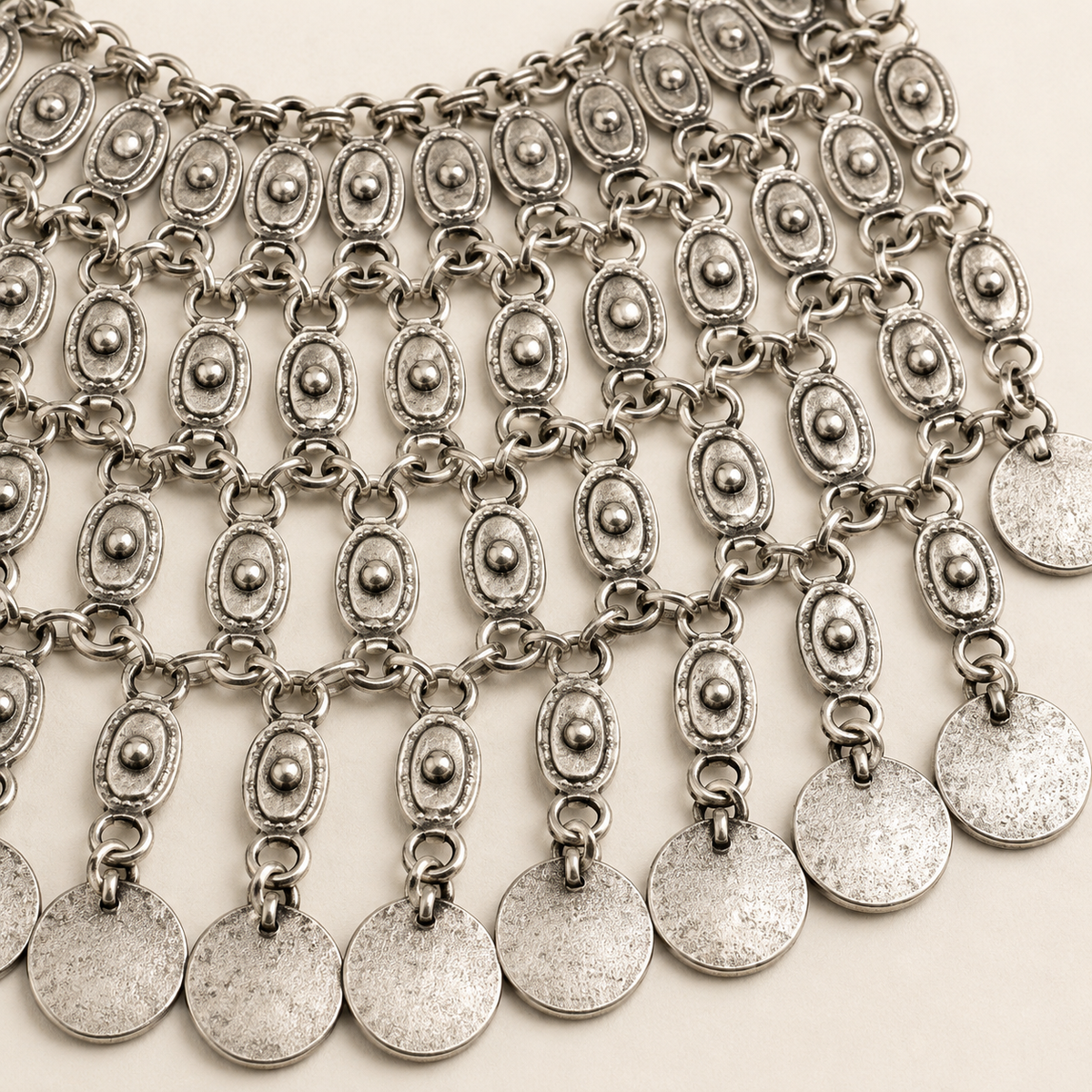 Close view of the textured oval links and coin fringe.