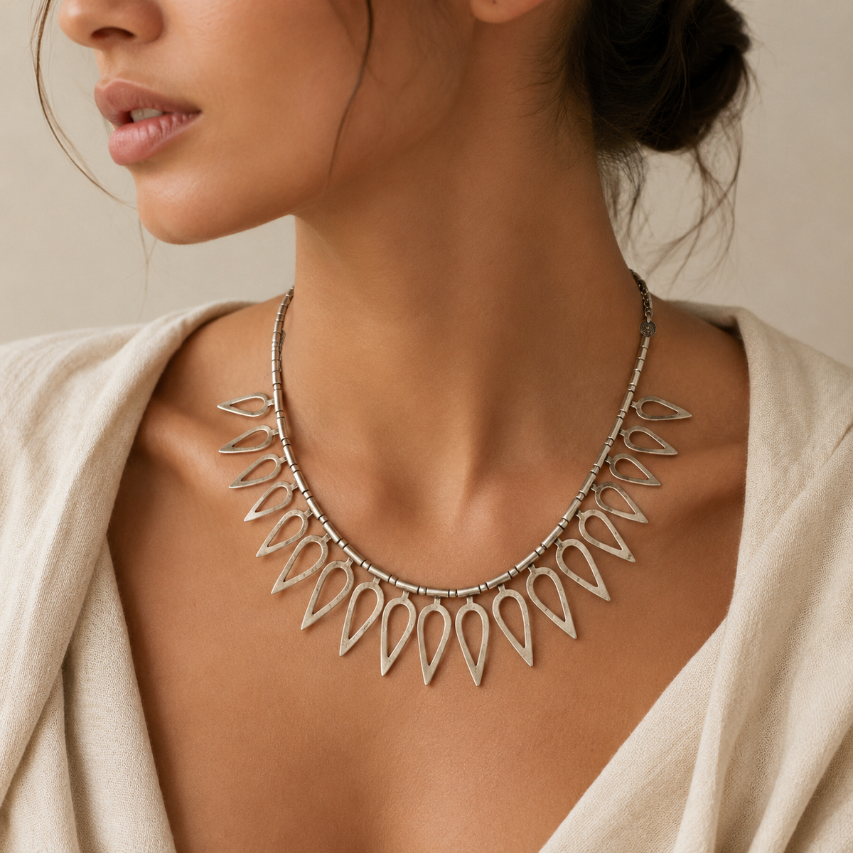 Silver-tone sculptural necklace with open teardrop details and a minimalist feel.