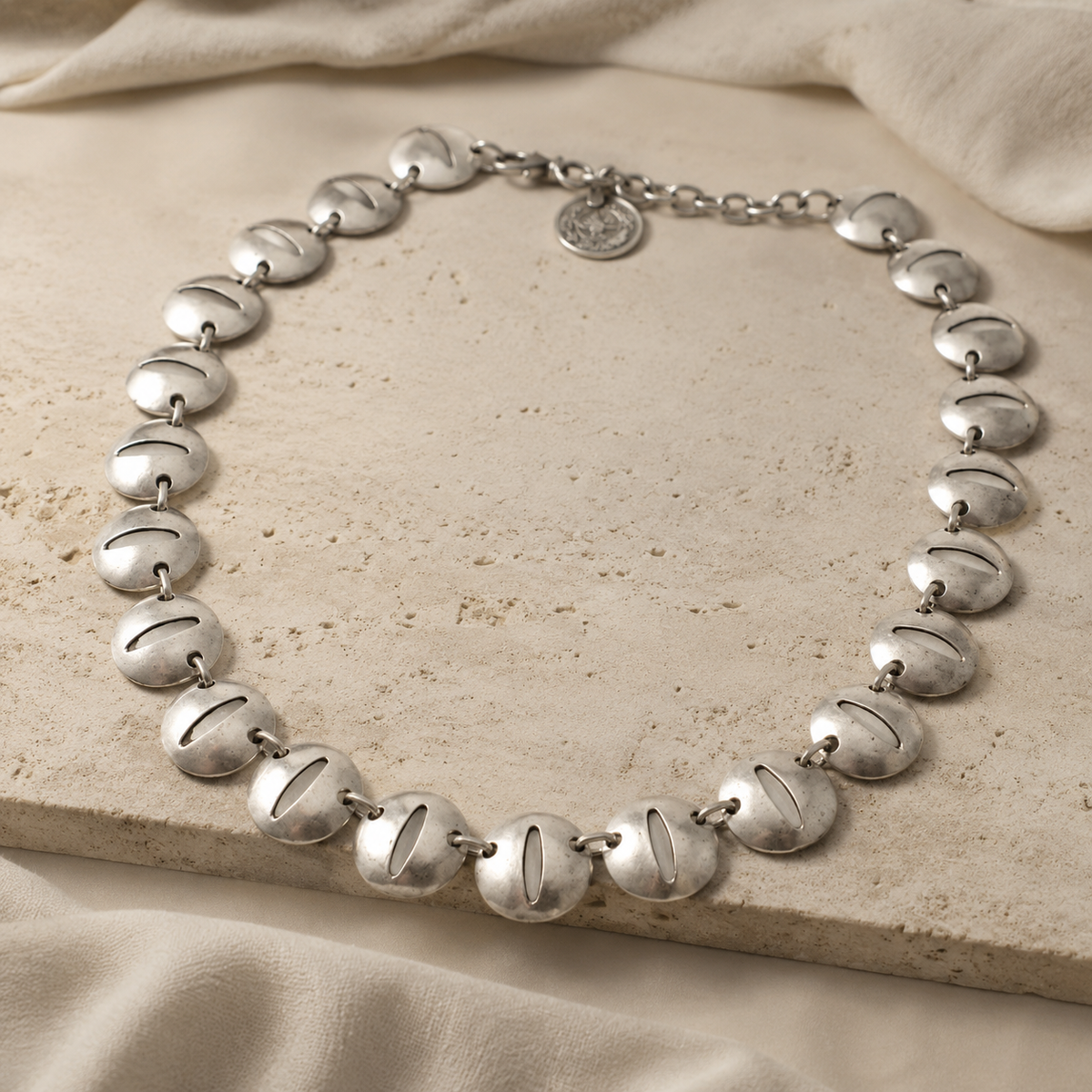 Angled view of a silver-tone oval disc link necklace.
