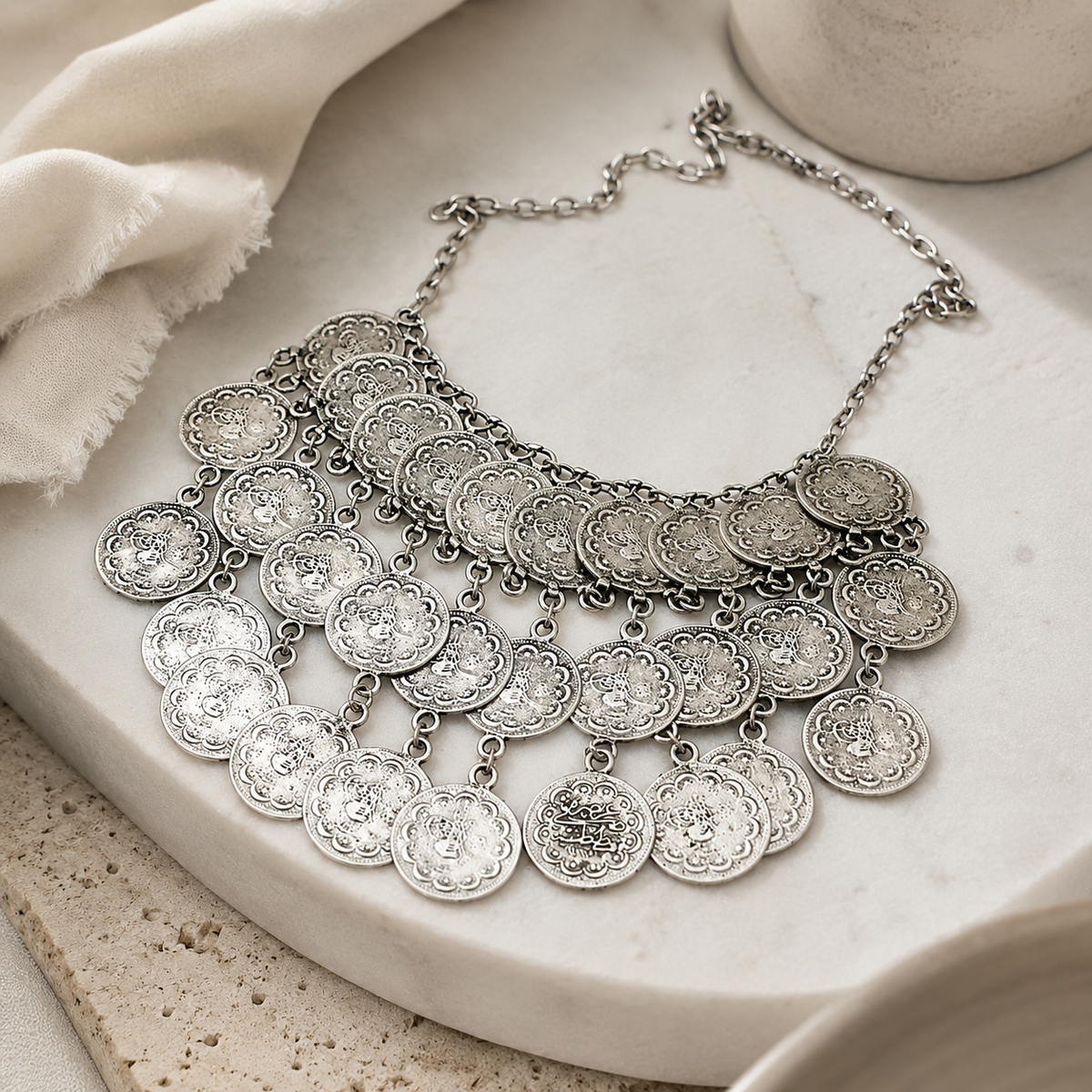 Angled view of a silver-tone layered coin bib necklace.