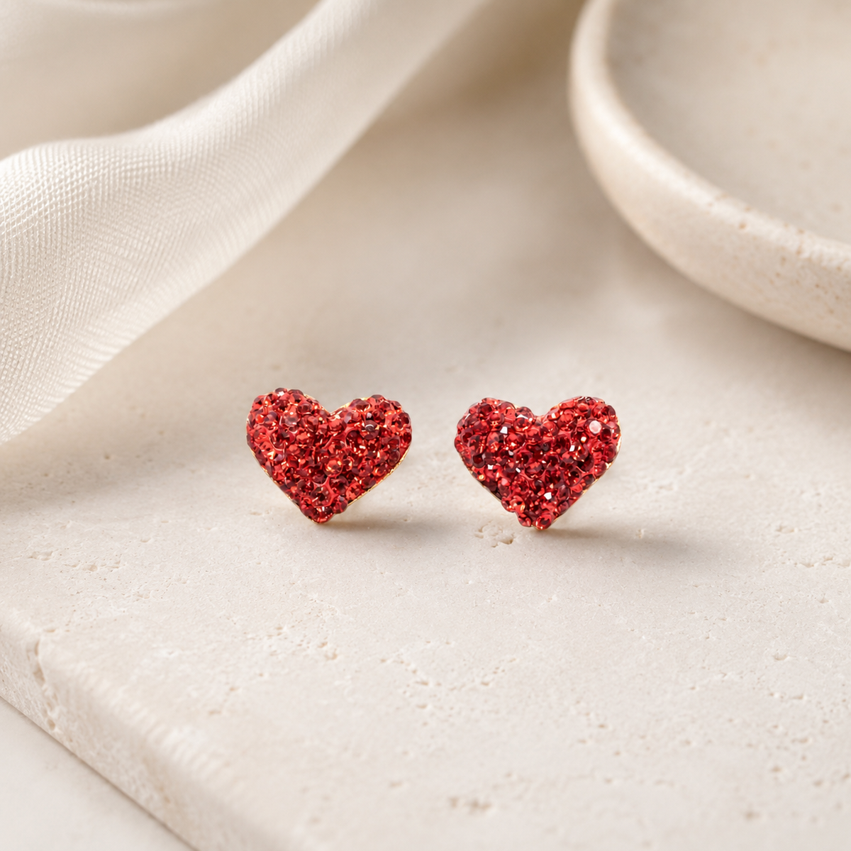 Red heart stud earrings with a gold-plated look styled on a white background.