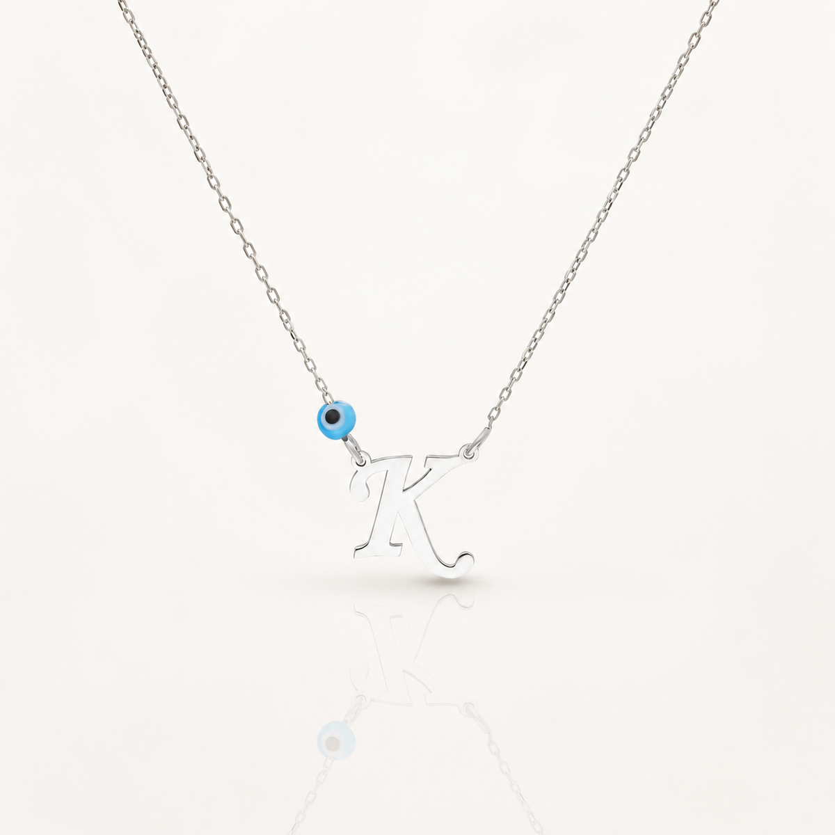 Silver-tone necklace with a personalized initial pendant and small blue evil eye accent.