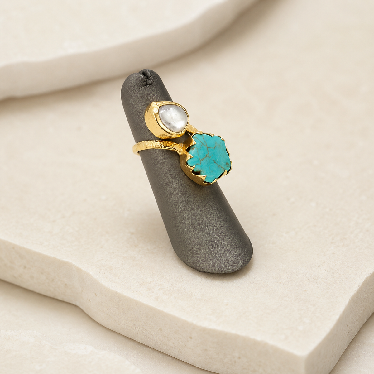 Angled view of a gold-plated ring with turquoise and pearl-like stones.