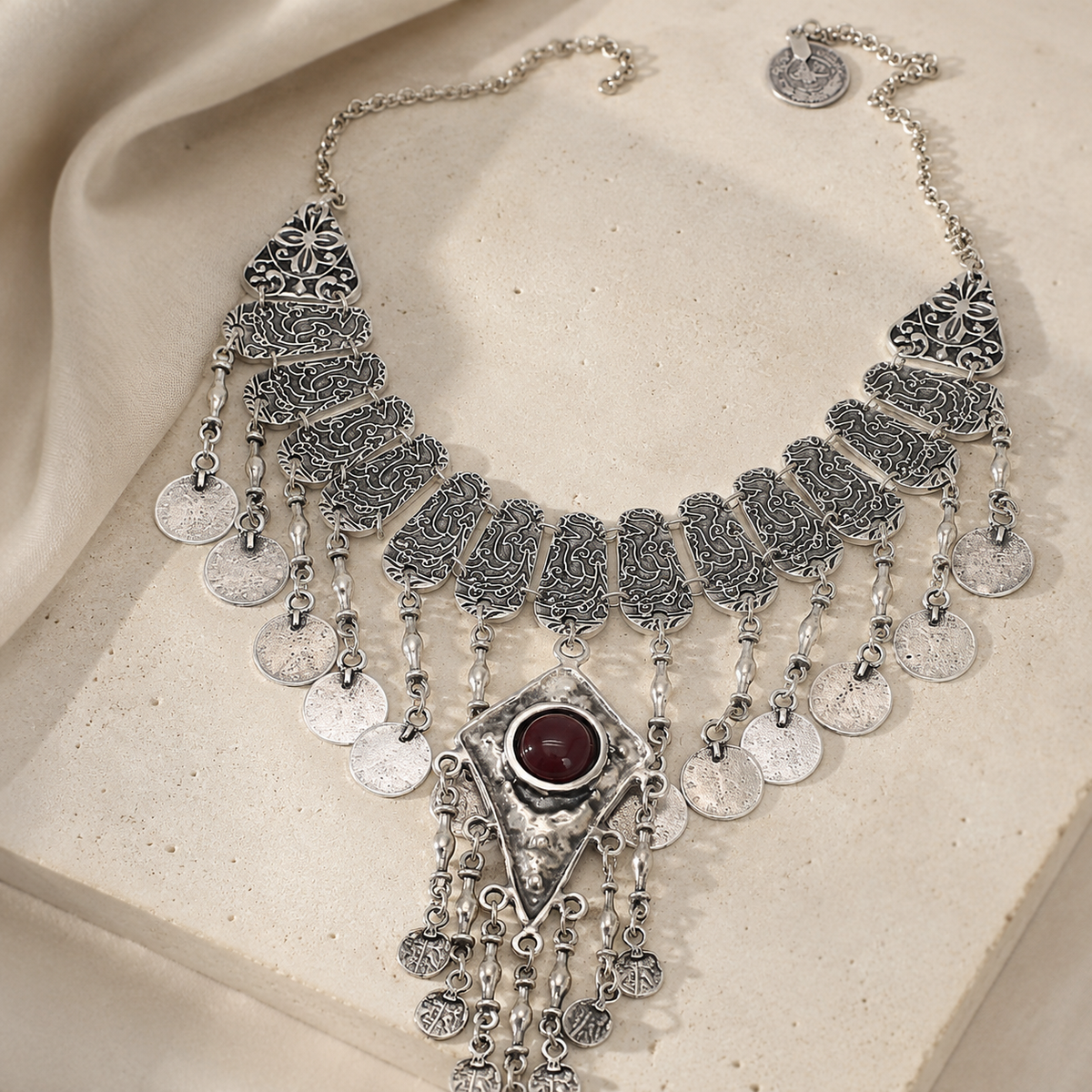 Silver-tone coin necklace with a tassel drop on a white background.