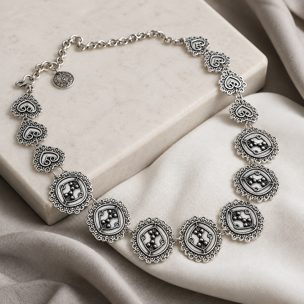 Angled view of a circle cluster link necklace with detailed silver-tone links.