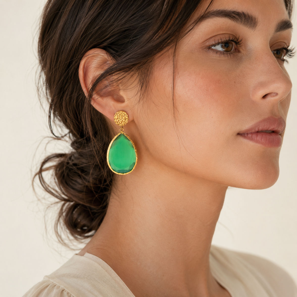 Gold-plated teardrop earrings with a faceted green smoky cat eye-style stone.