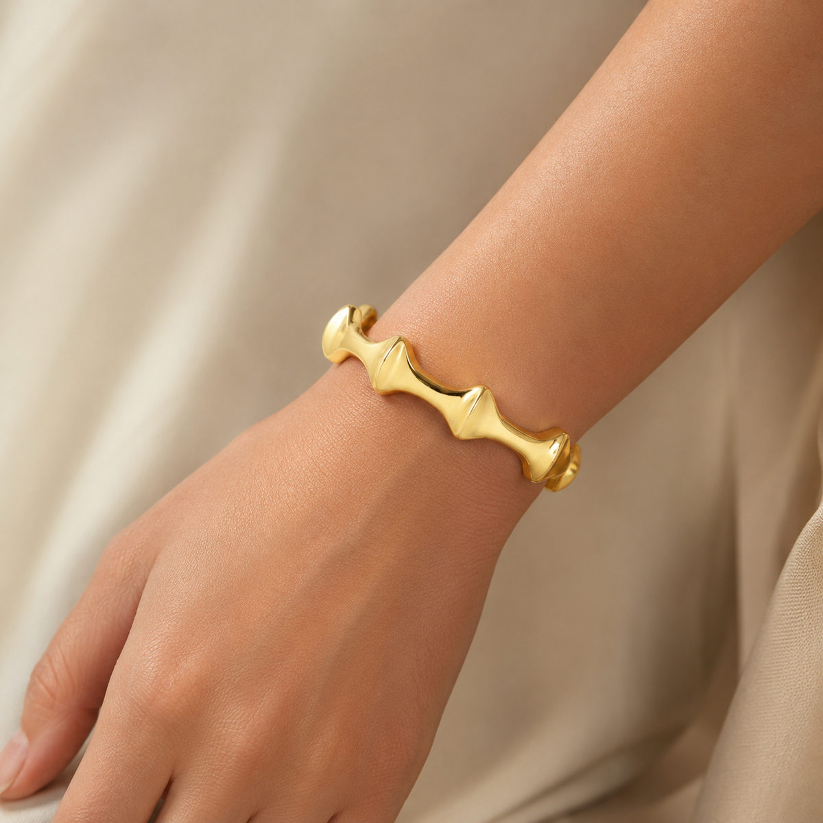 A polished gold-tone open cuff bracelet shown from the front.