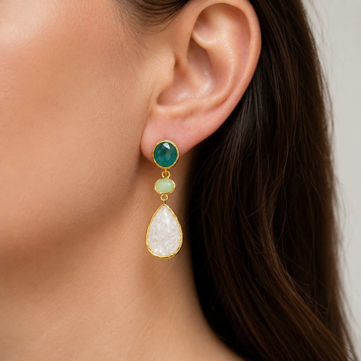Gold-plated dangle earrings shown front view with faceted green and clear stones.