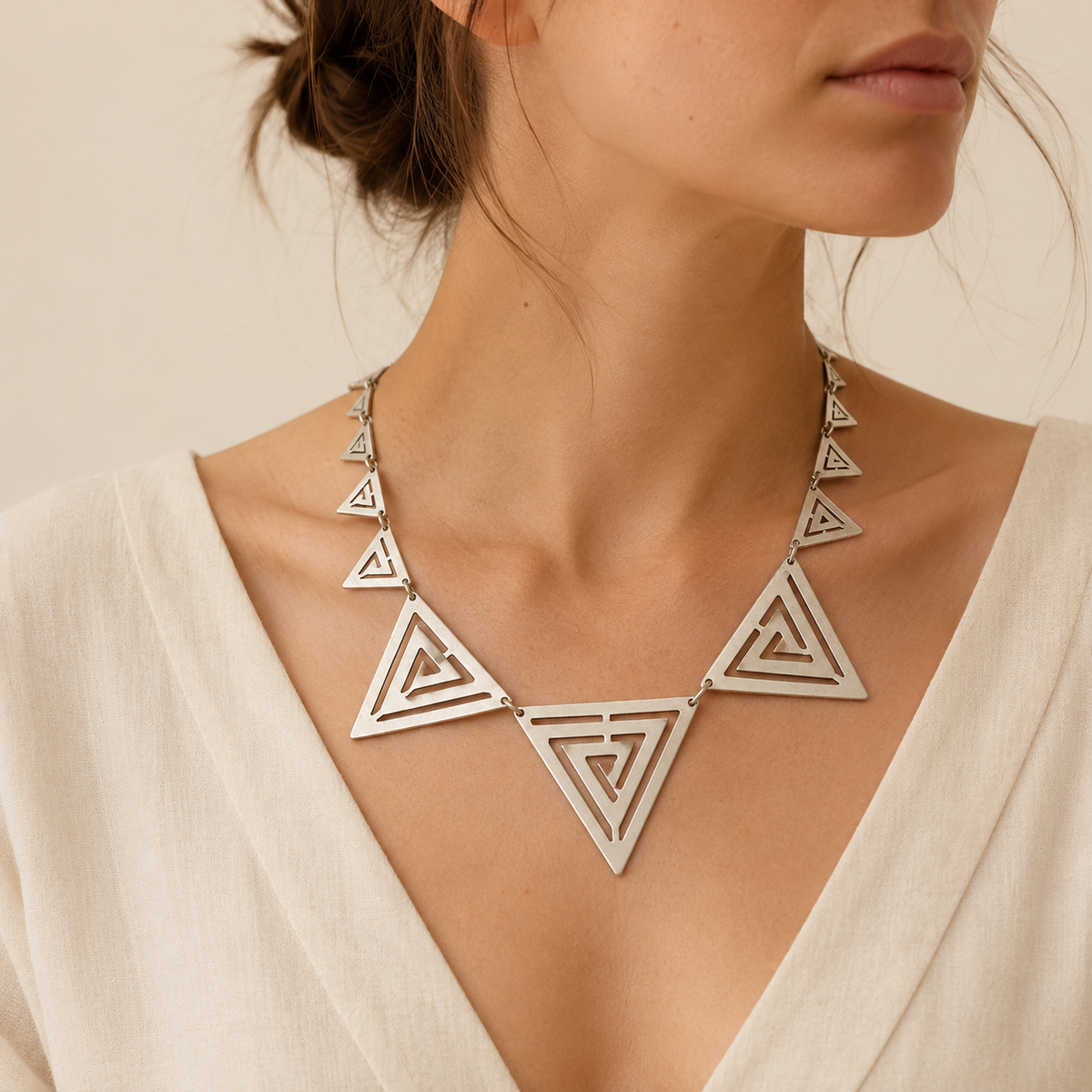 Silver-tone triangle cutout statement necklace shown on a white background.