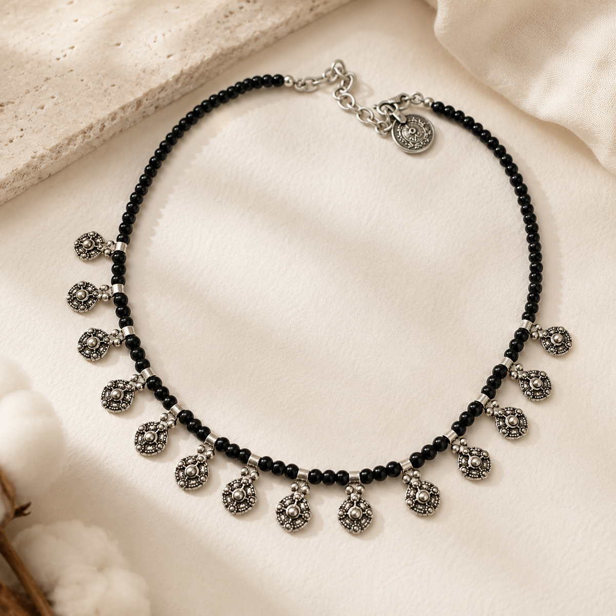 Black bead charm necklace styled on a white background.
