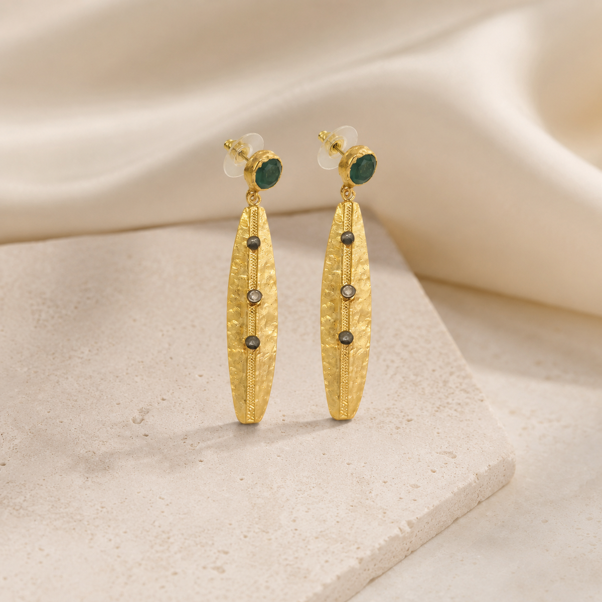 Gold-tone drop earrings with olive green stone accents on a white background.
