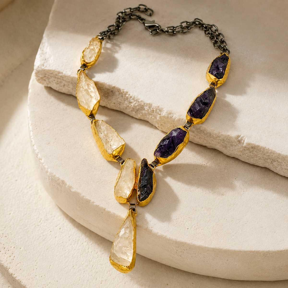 Angled view of a Y necklace with purple and crystal-like stones and a gold-tone finish.