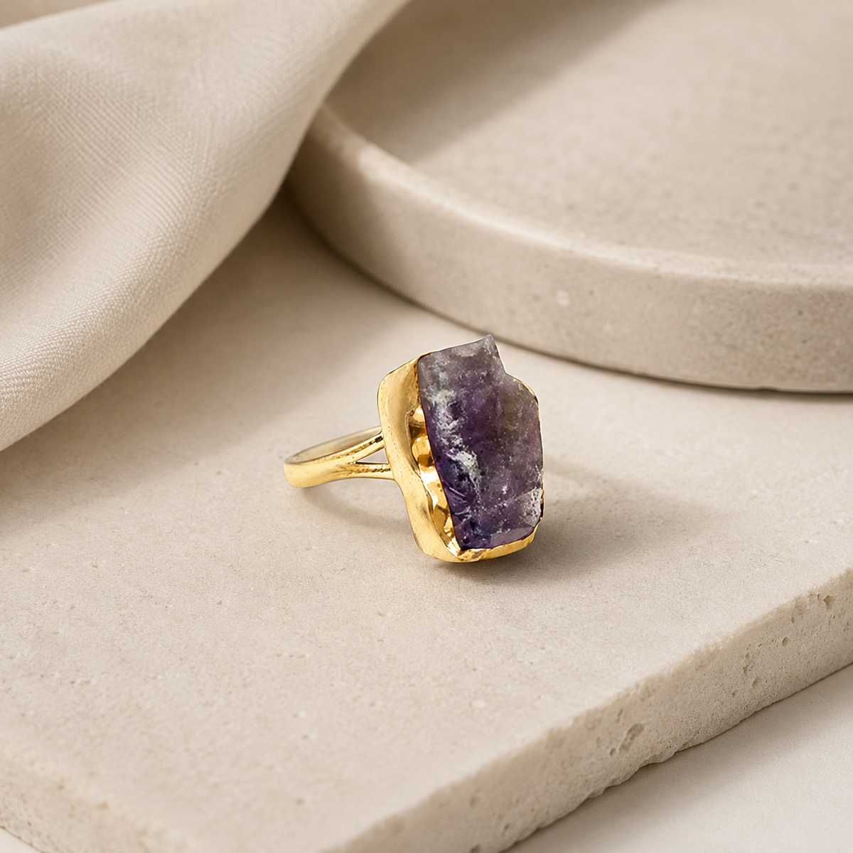 Angle view of a raw amethyst ring with a gold-plated setting.