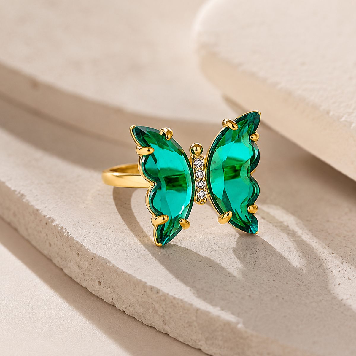 Angled view of a butterfly ring with crystal-green wings and gold-tone details.