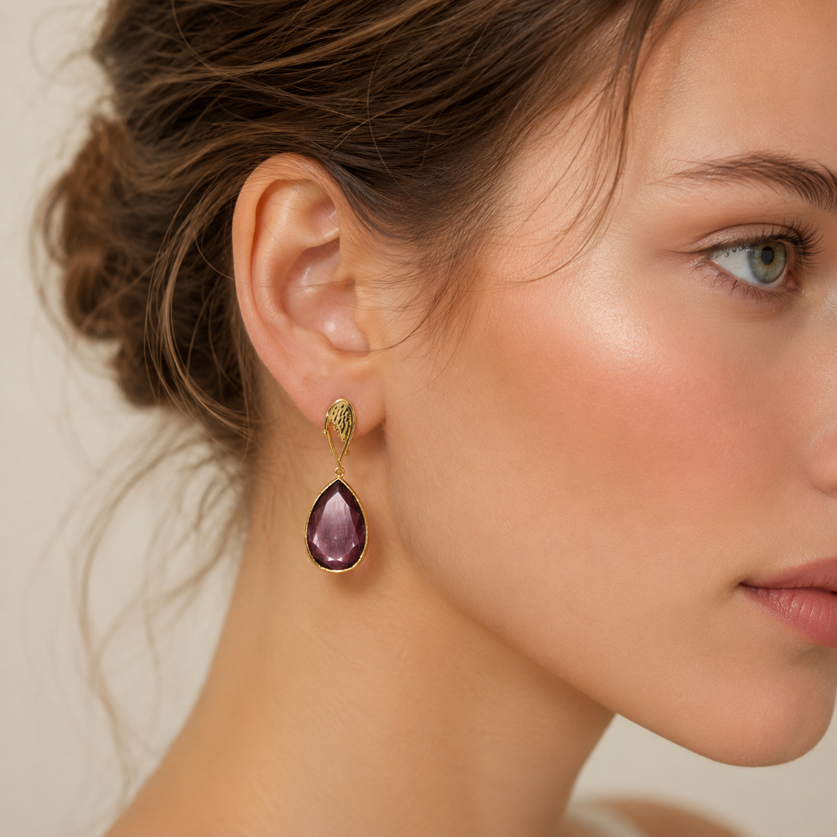 Gold-plated drop earrings with a purple teardrop stone.