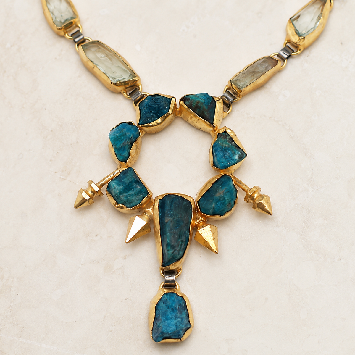 Close view of the teal raw stone and gold-tone setting.