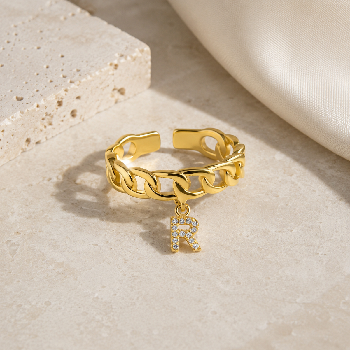 Gold-tone initial ring with a chunky chain silhouette.