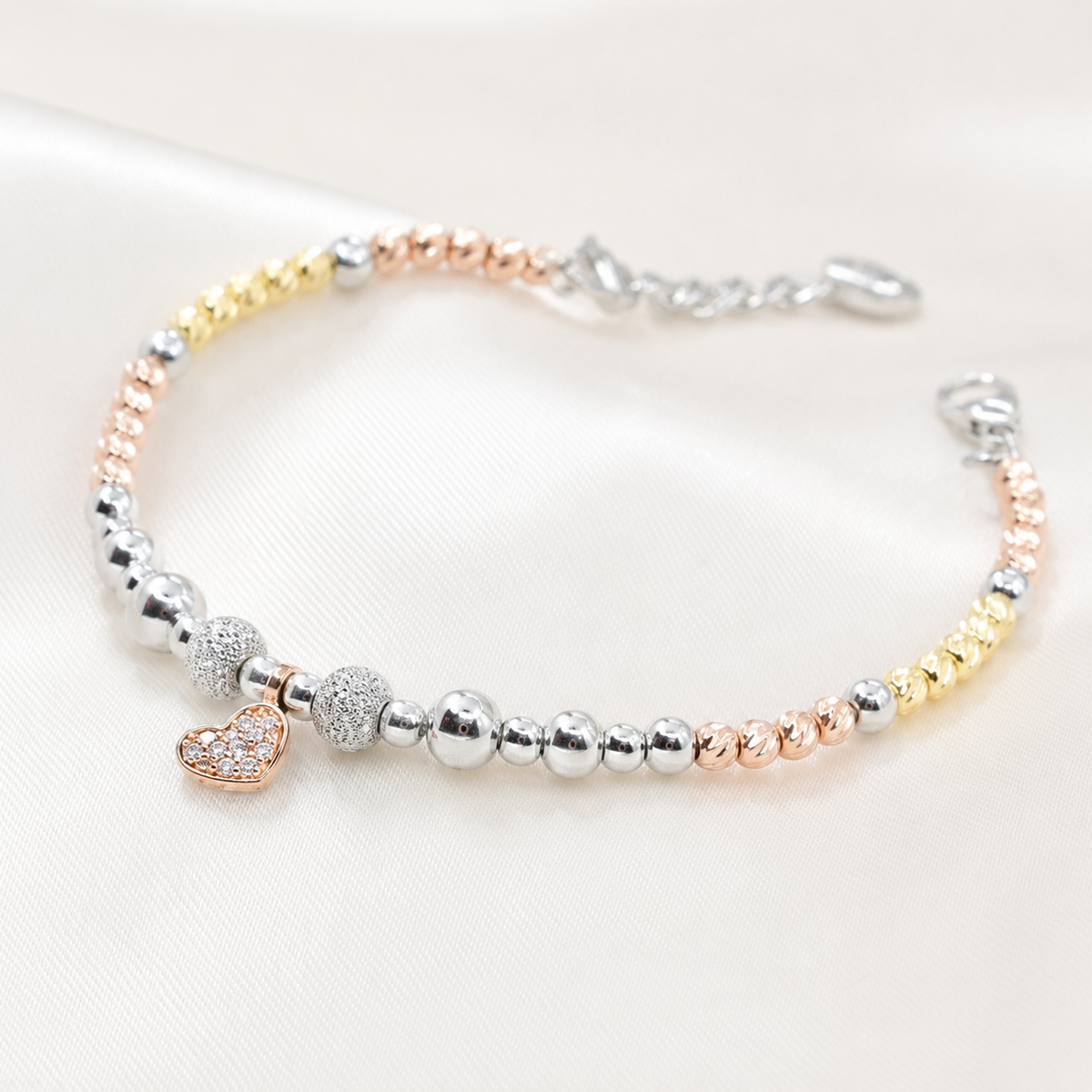 Close view of the beaded bracelet with a heart charm and polished mixed-metal finish.