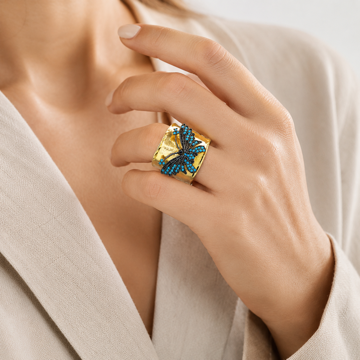 Gold-plated wide band ring with a butterfly motif and turquoise blue accents.