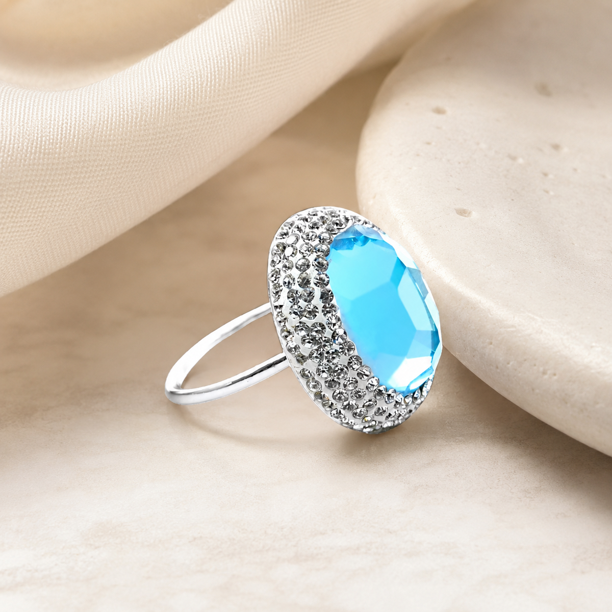 Silver-tone ring with a bright baby blue center stone on a white background.