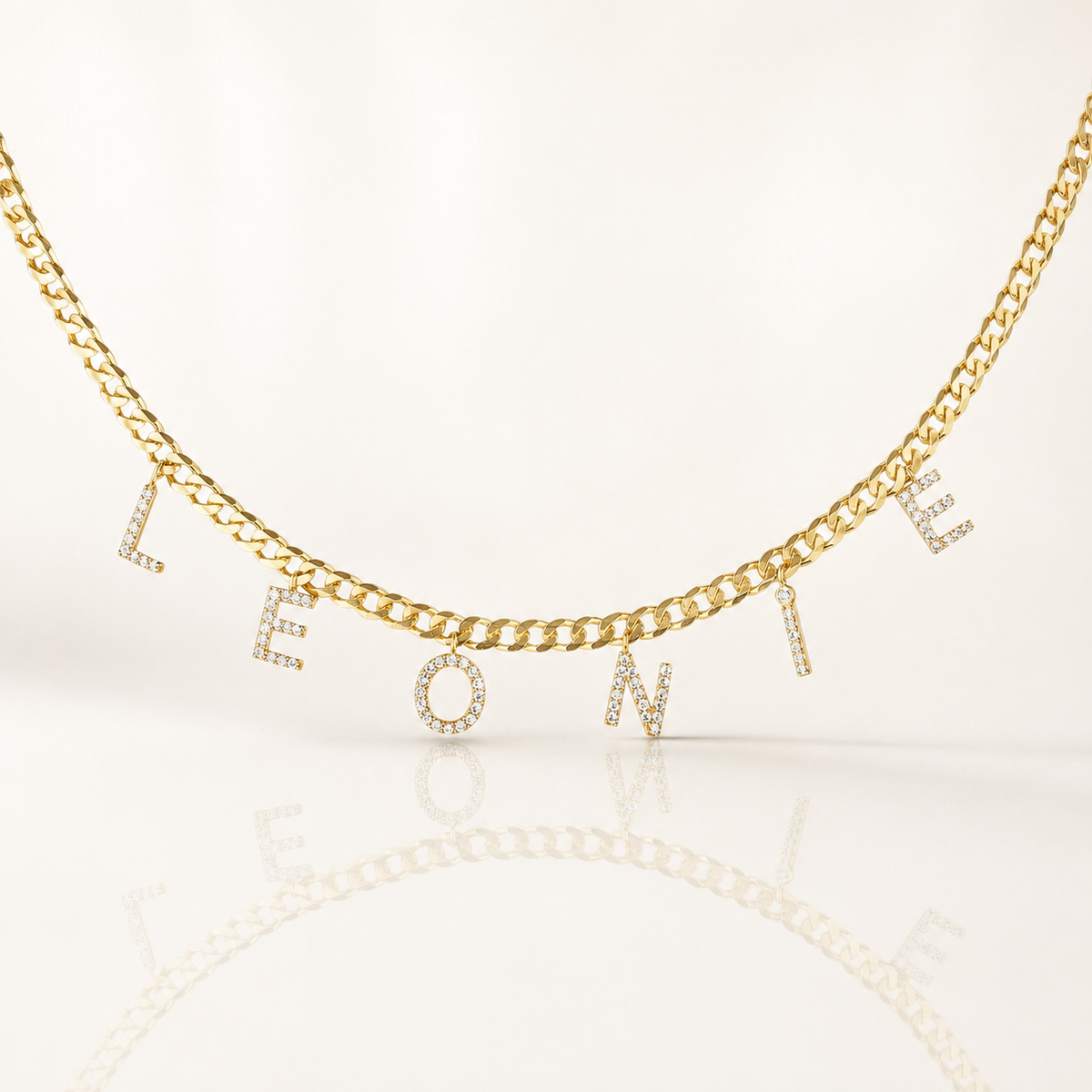 Gold-tone curb chain necklace with CZ letter charms spelling a personalized name.