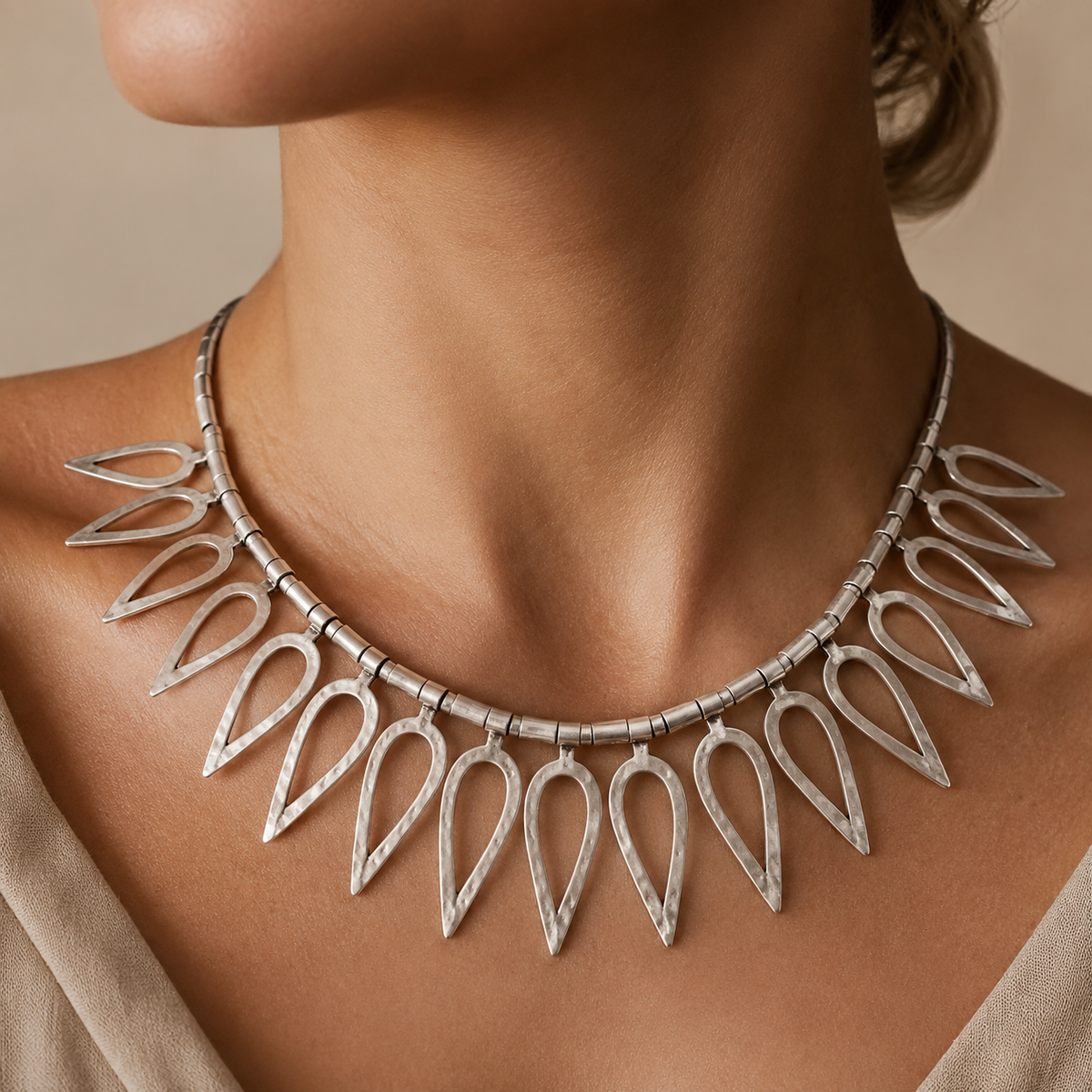 Silver-tone teardrop collar necklace shown from above on a white background.