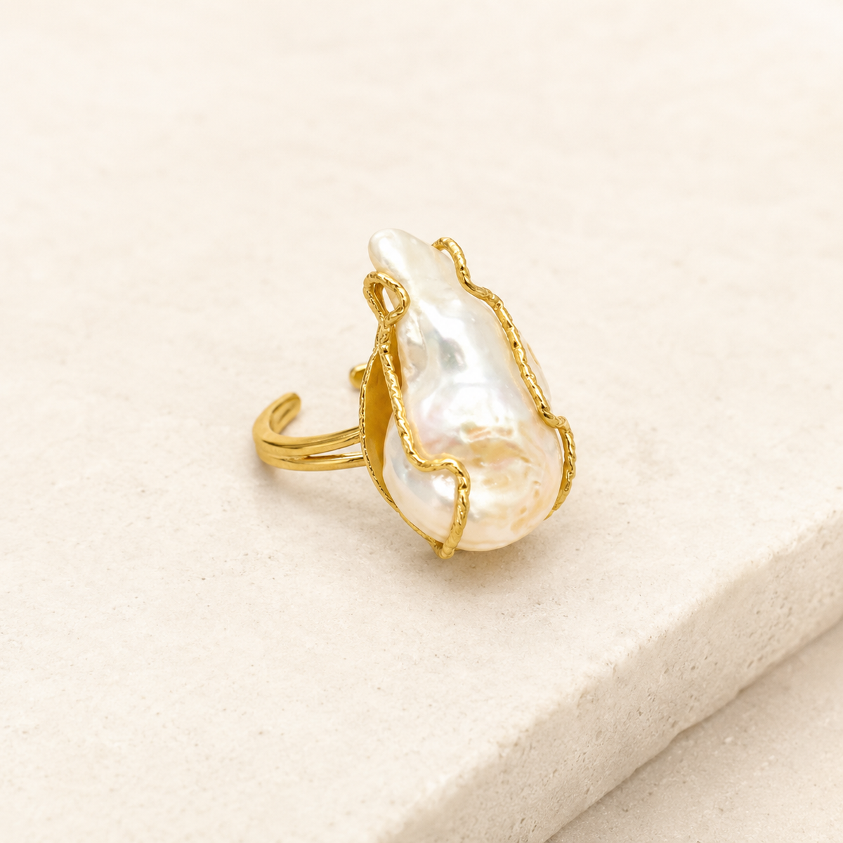 Angled view of a baroque pearl statement ring in gold-plated metal.