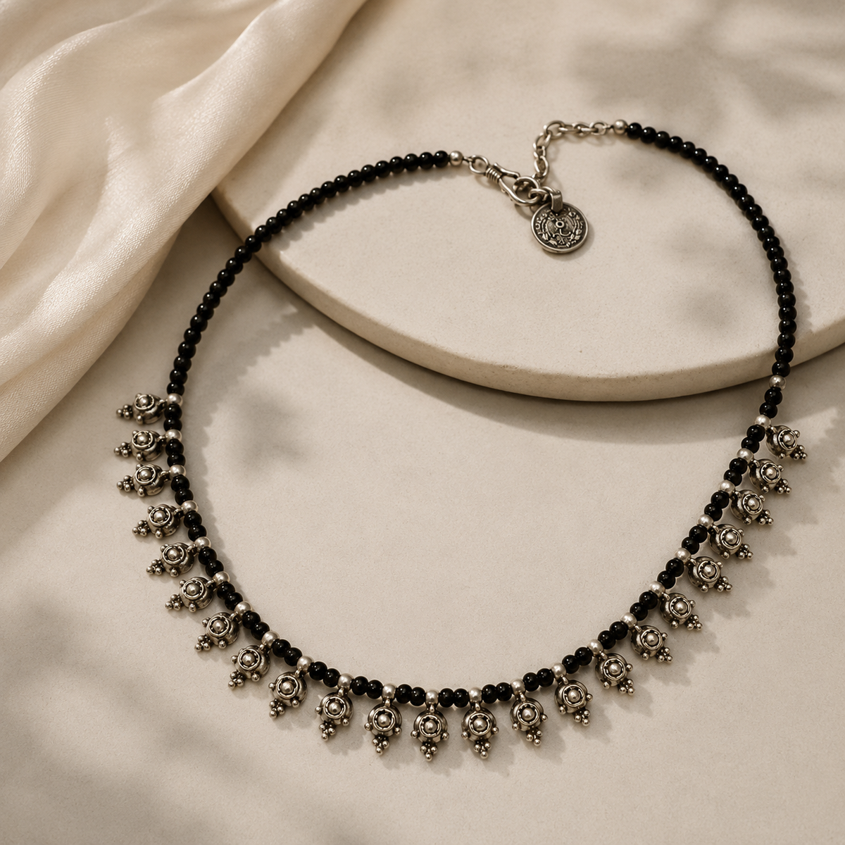 Black bead necklace with silver-tone dangles styled as a statement piece.