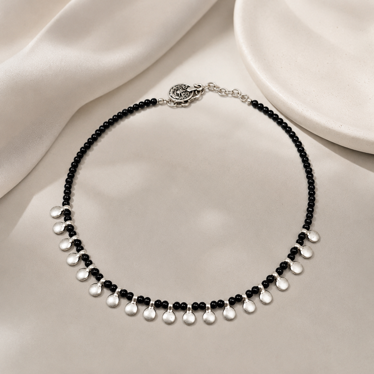 Black bead necklace with silver disc accents styled in a clean product view.