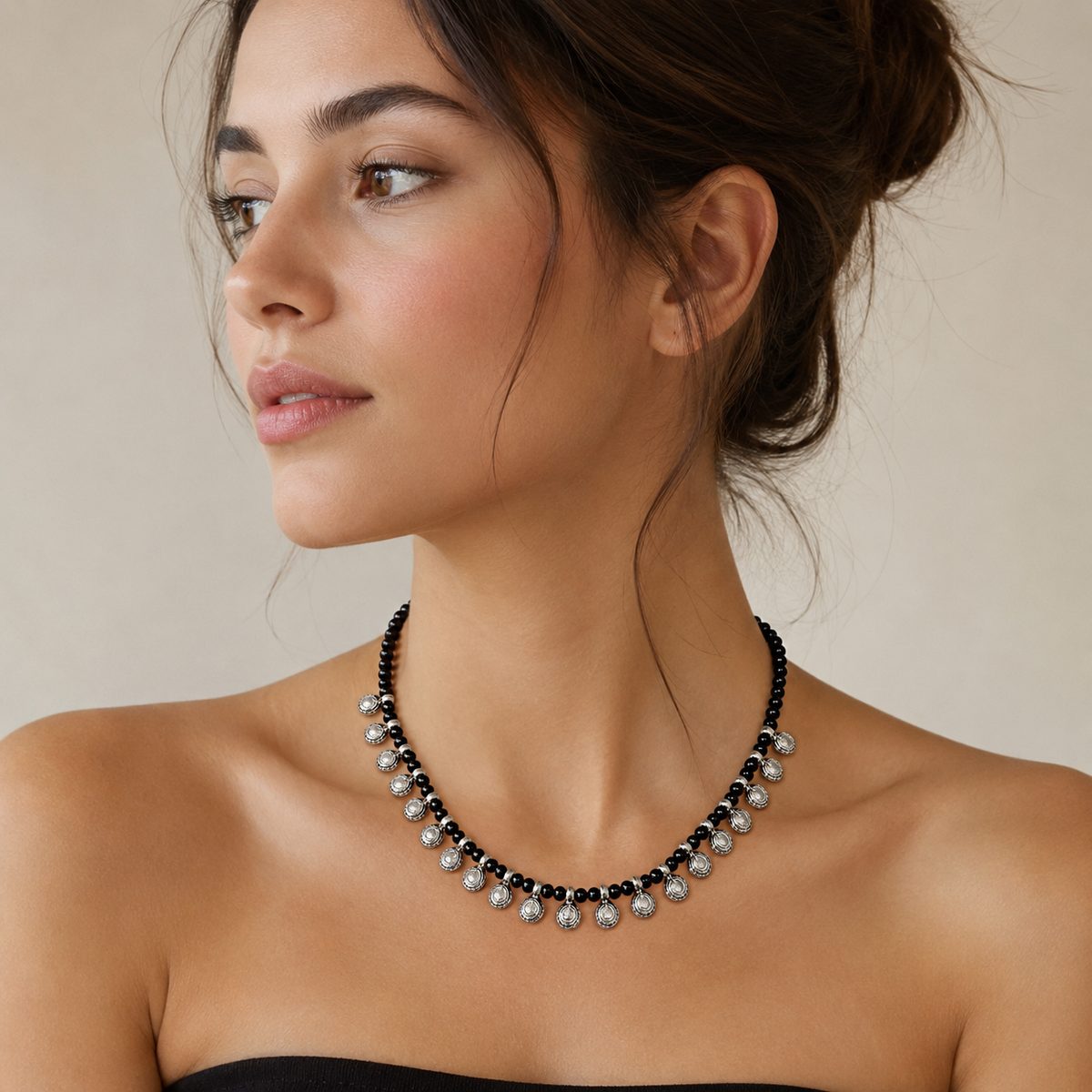 Black bead necklace with round silver-tone charms shown from above.