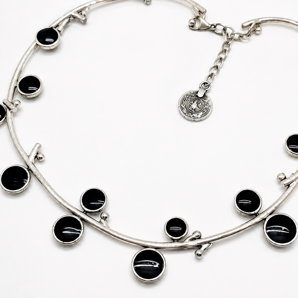 Close view of the silver-tone necklace with glossy black stone accents and a small pendant charm.