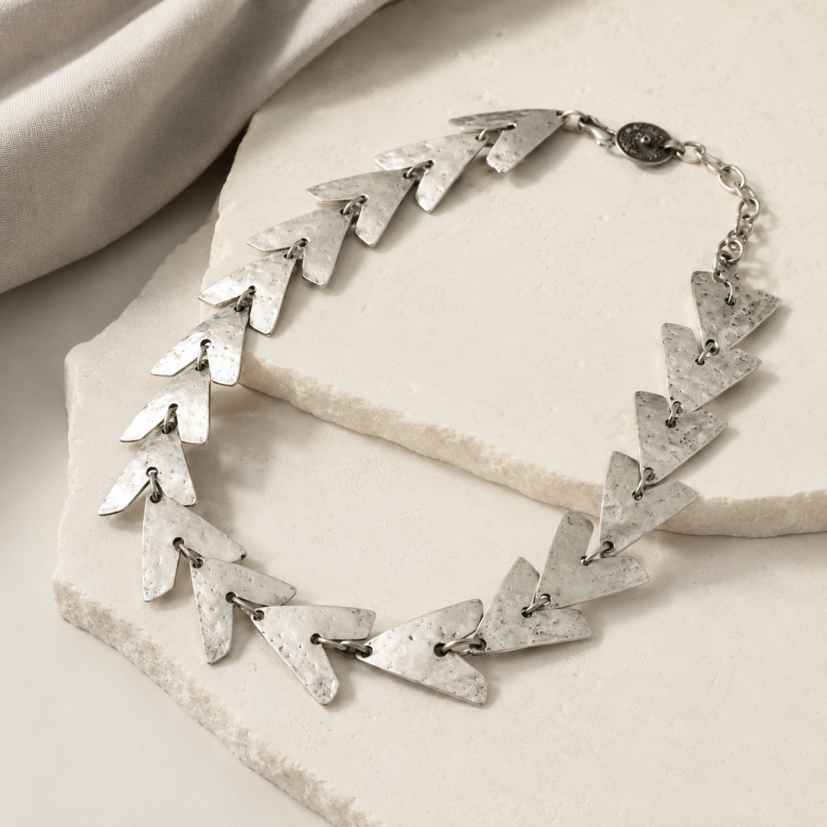 Angled view of the triangle link necklace with textured metal finish.