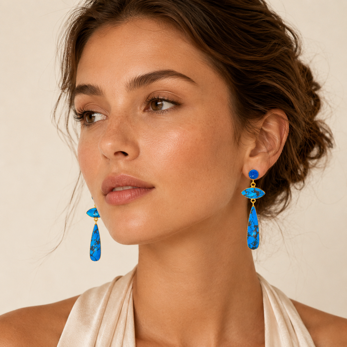 Gold-plated earrings with turquoise-inspired stones and a long dangling shape.