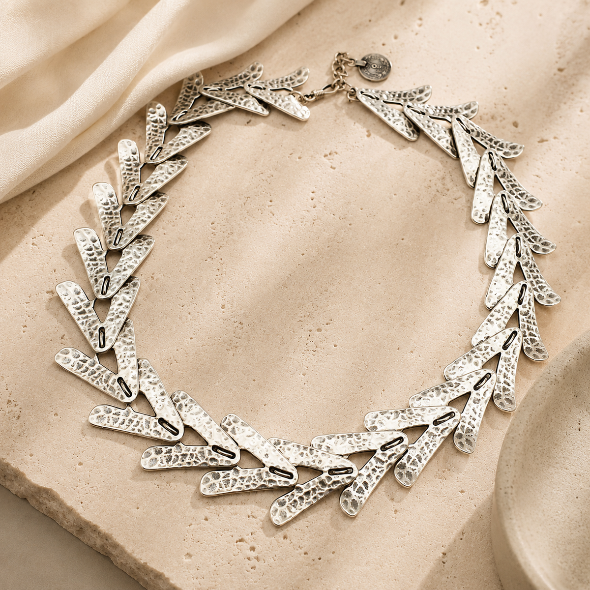 Silver-tone collar necklace with sculptural arrow links for modern styling.