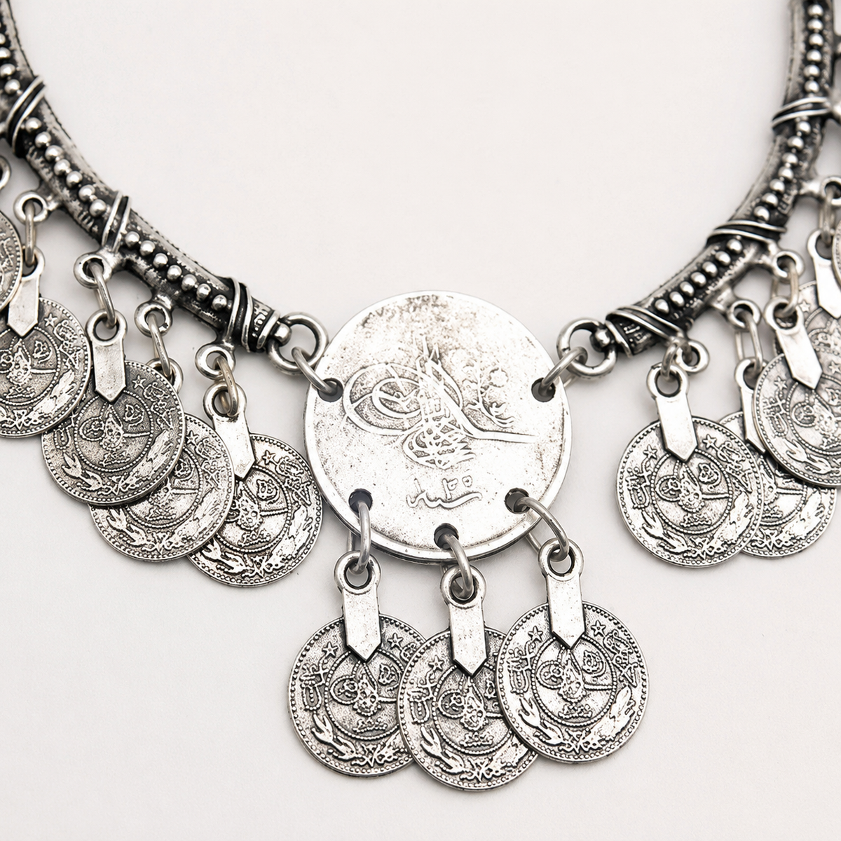 Close view of the engraved crescent pendant and dangling coin details.