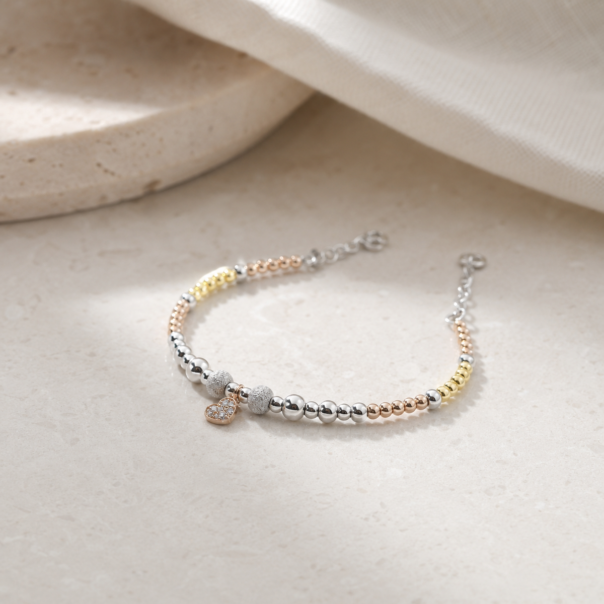A mixed-metal beaded bracelet with a polished finish and heart charm.