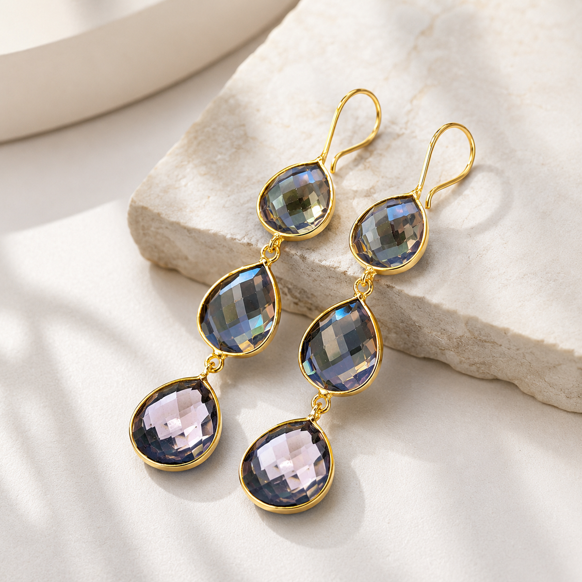 Angled view of triple teardrop earrings with faceted smoky stones and gold-plated trim.