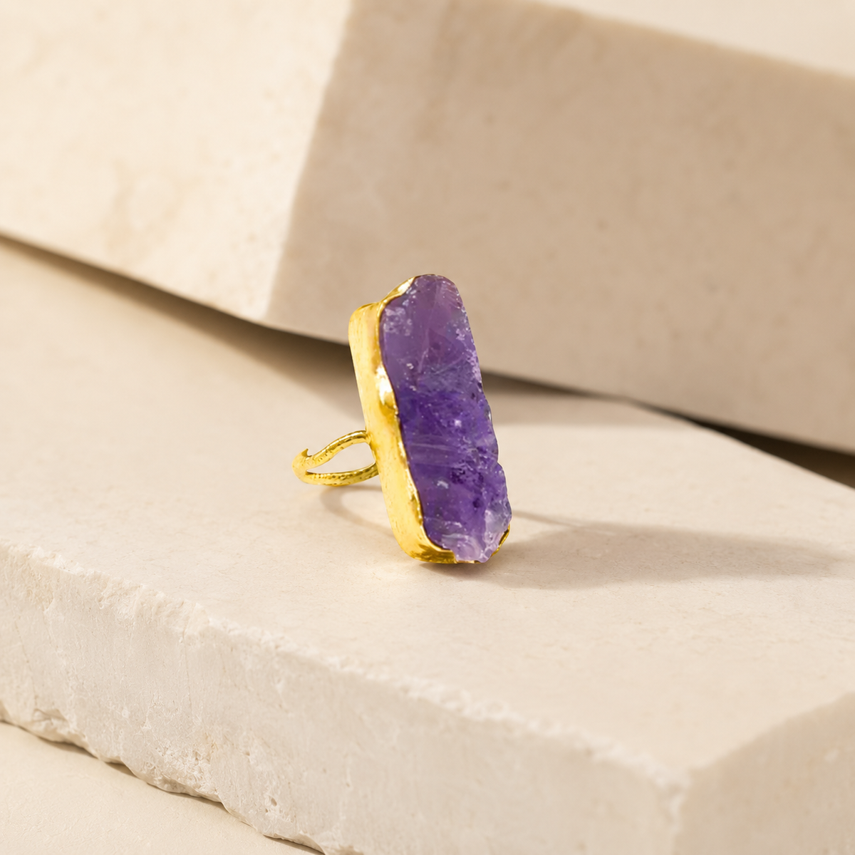 Side angle of a raw amethyst bar ring in gold plating.