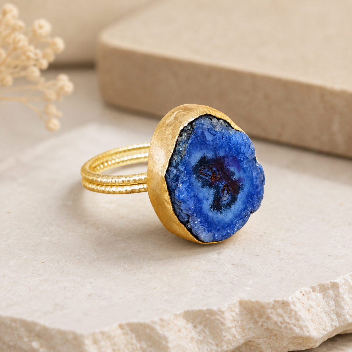 Side angle view of a blue druzy agate ring with a gold-tone setting.