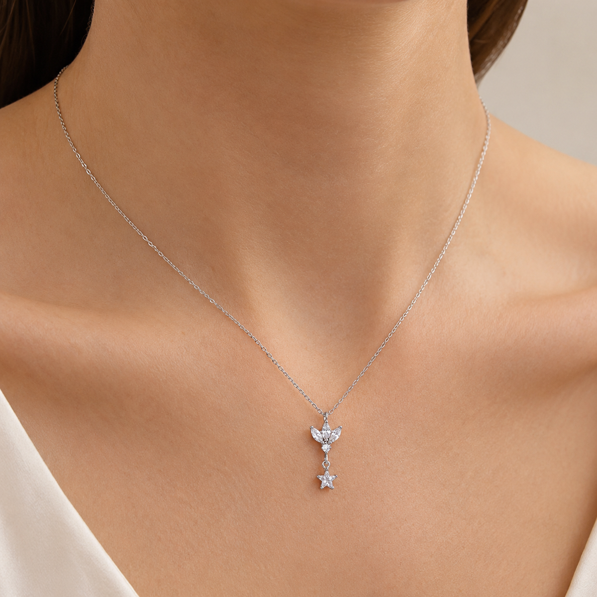 A silver-tone pendant necklace with a lotus-inspired charm and clear star drop.